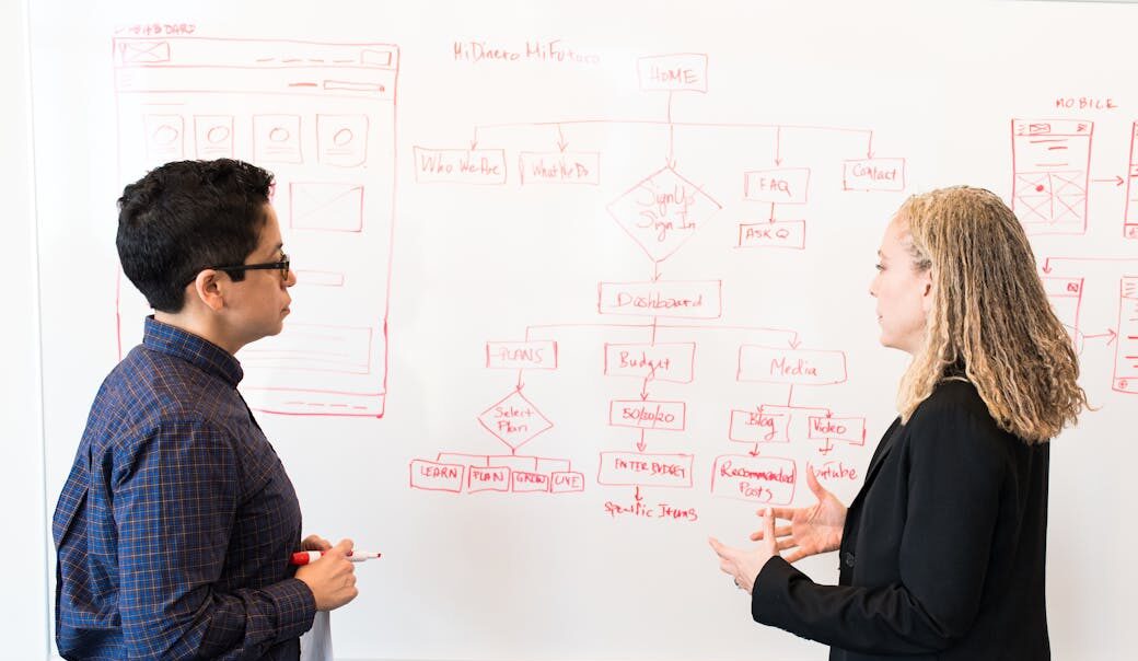 Two professionals brainstorming digital marketing ideas on a whiteboard.